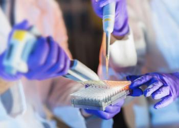 Cientistas trabalhando em um laboratório segurando uma pipeta enquanto enchem tubos de ensaio